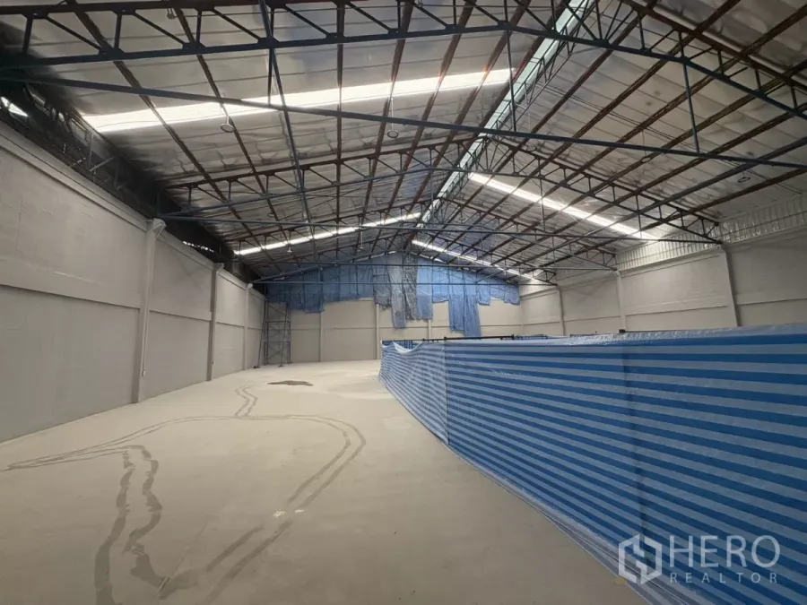 工厂 出租在Bang Phli, Samut Prakan - 高挑钢结构屋顶的宽敞仓库内部，带采光板与抛光混凝土地面。