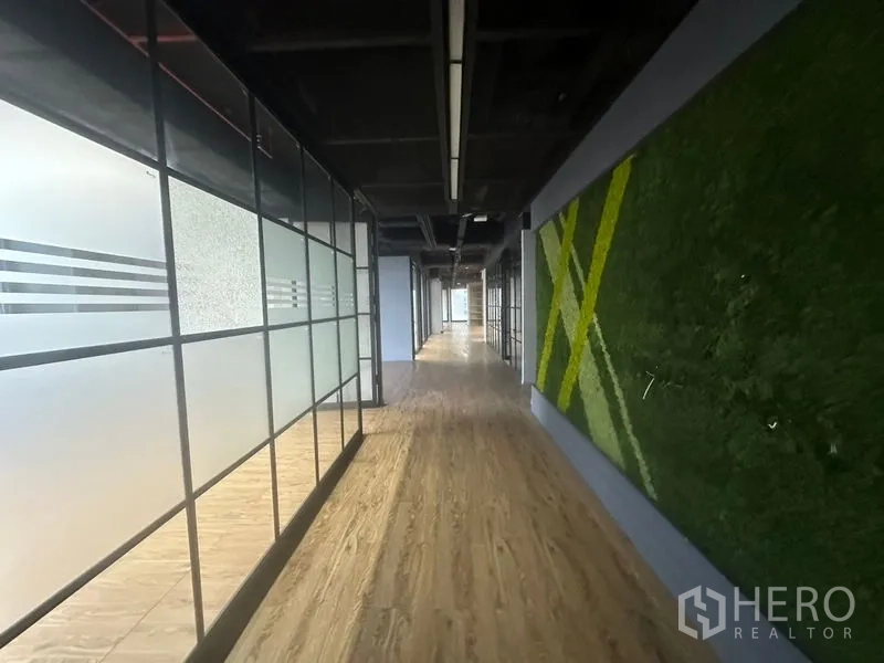 Office Space for rent in Bang Rak, Bangkok - Corridor with frosted glass partitions, wood flooring, and a green feature wall in a modern office.