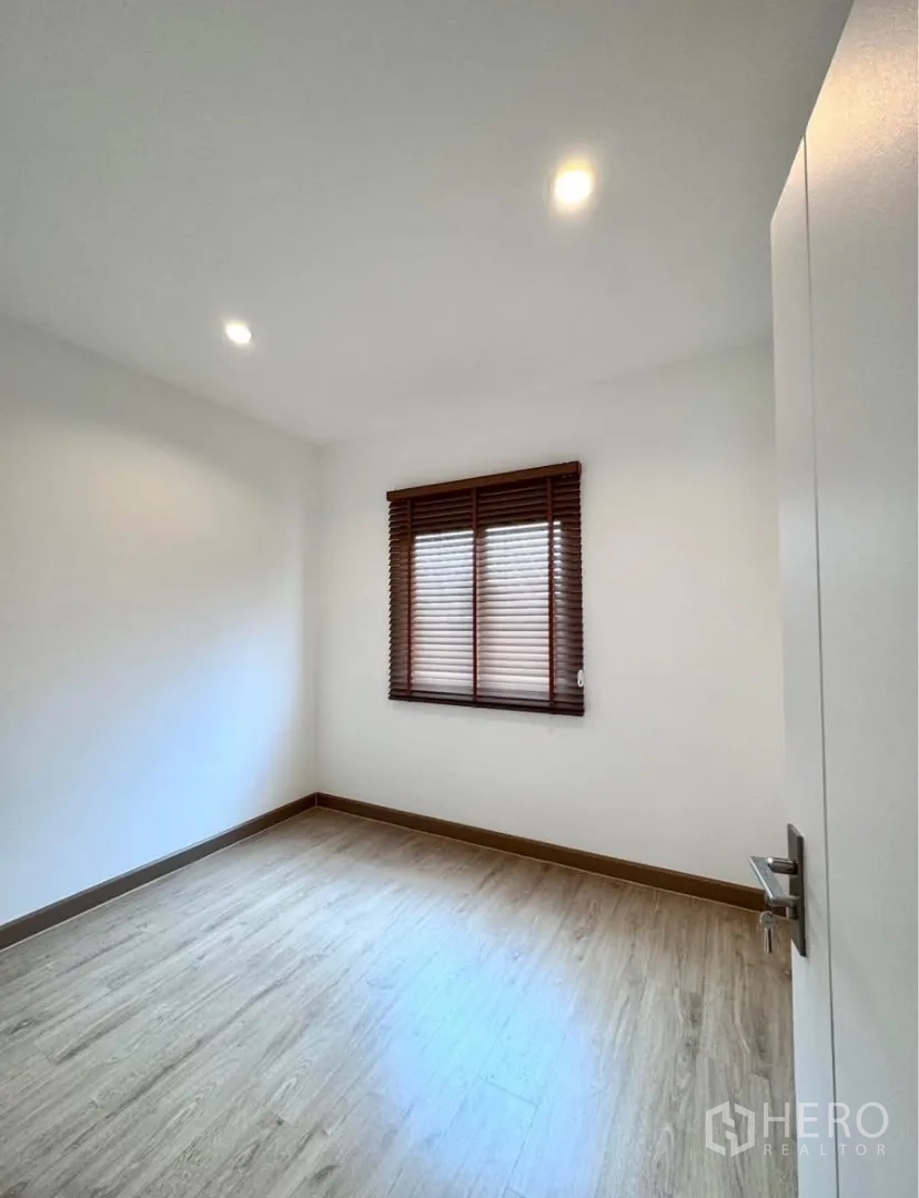 Detached House for rent in Samut Prakan - Compact bedroom with window blinds and wood floor.