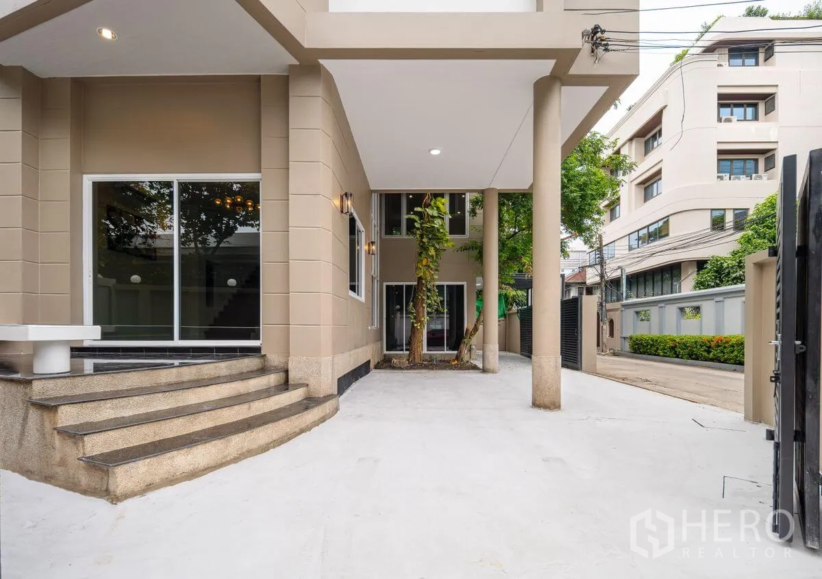 Detached House for rent or sale in Chatuchak, Bangkok - Gated driveway and covered porch with columns, sliding glass doors, and exterior lighting.