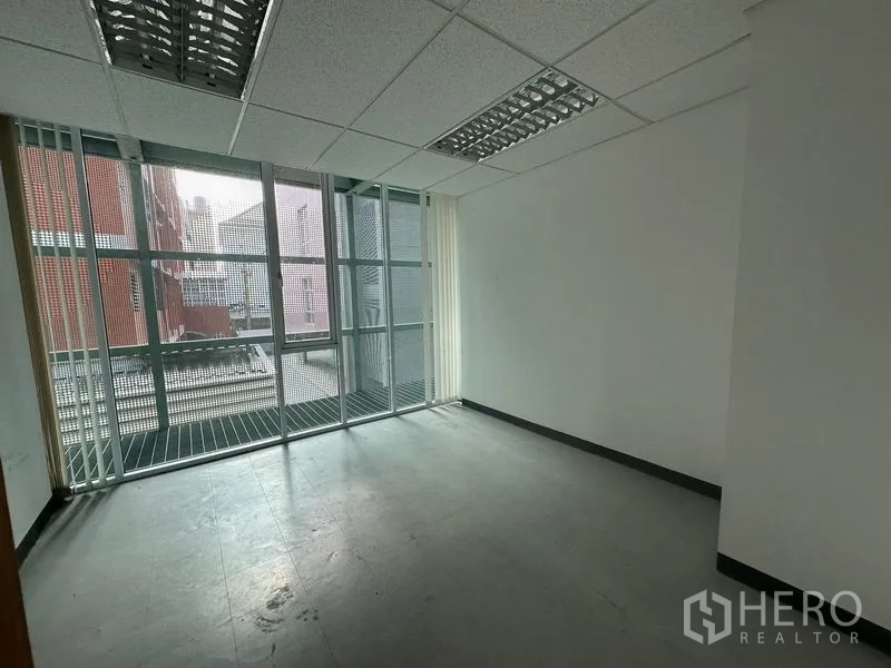 Office Space for rent - Vacant room with large window wall and exterior grate platform, ready for customization.