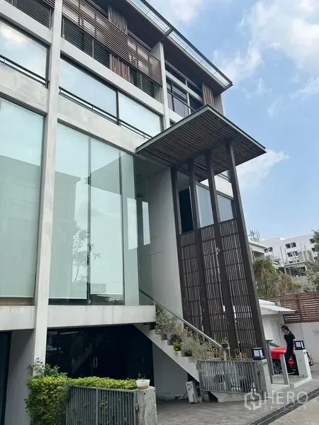 Home Office for rent in Phra Khanong, Bangkok - Contemporary townhouse-style exterior with large glass panels and landscaped entry.