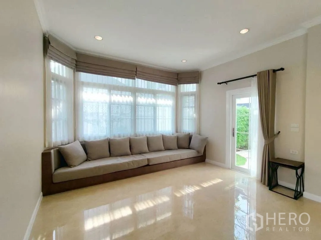 Detached House for rent in Bang Na, Bangkok - Bright living area with long built-in sofa and garden access door.