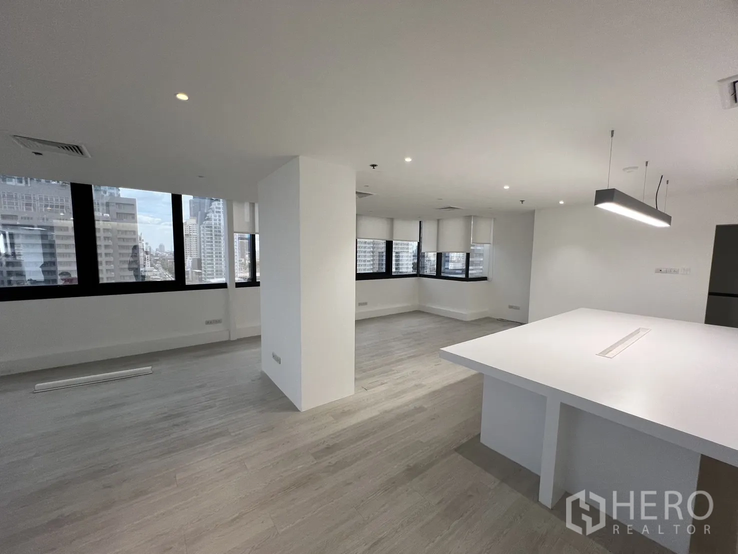 Office Space for rent in Khlong Toei, Bangkok - Bright office with a structural column, recessed lighting and city views from black‑framed windows.