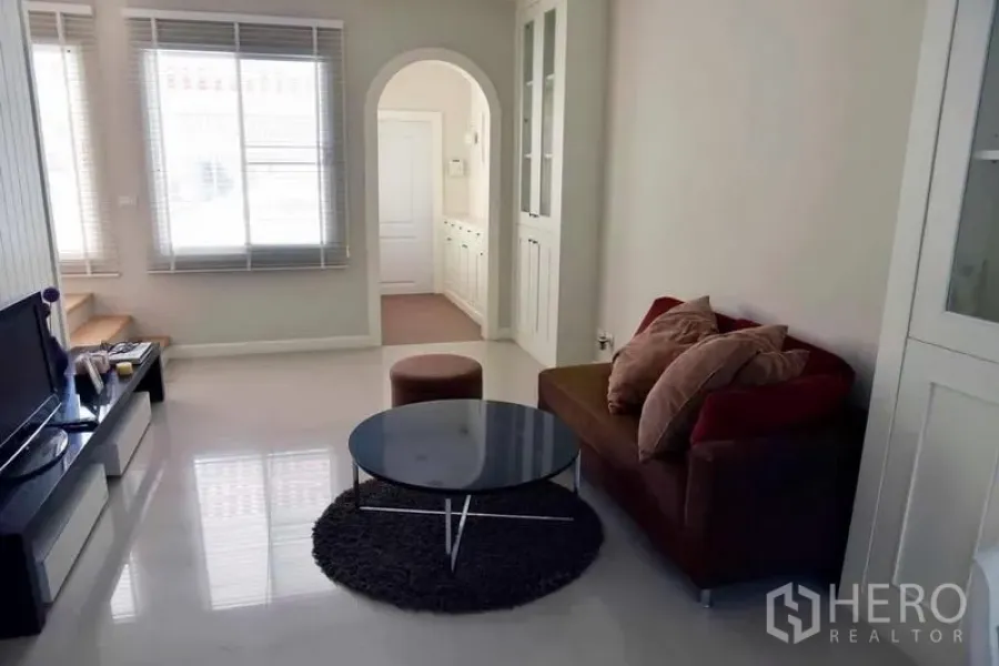 联排别墅 出租或出售在Wang Thonglang, Bangkok - 通透客厅，设大窗、沙发、电视柜和拱形门洞。