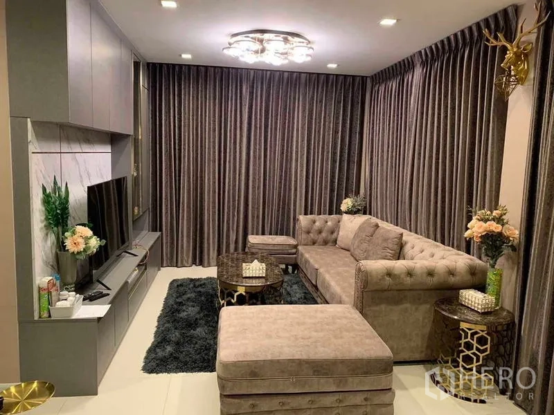 独立式住宅 出售在Khan Na Yao, Bangkok - 温馨起居室，纽扣靠背沙发、电视背景墙与吊灯、深色窗帘。