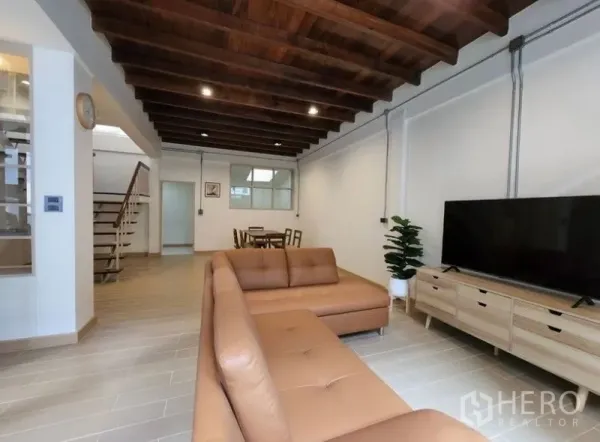 Townhouse for sale - Bright living room with leather sectional sofa, TV console and timber beam ceiling.