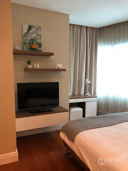 公寓 出租或出售在Khlong Toei, Bangkok - 卧室一角，挂墙电视、开放置物架与小型书桌。