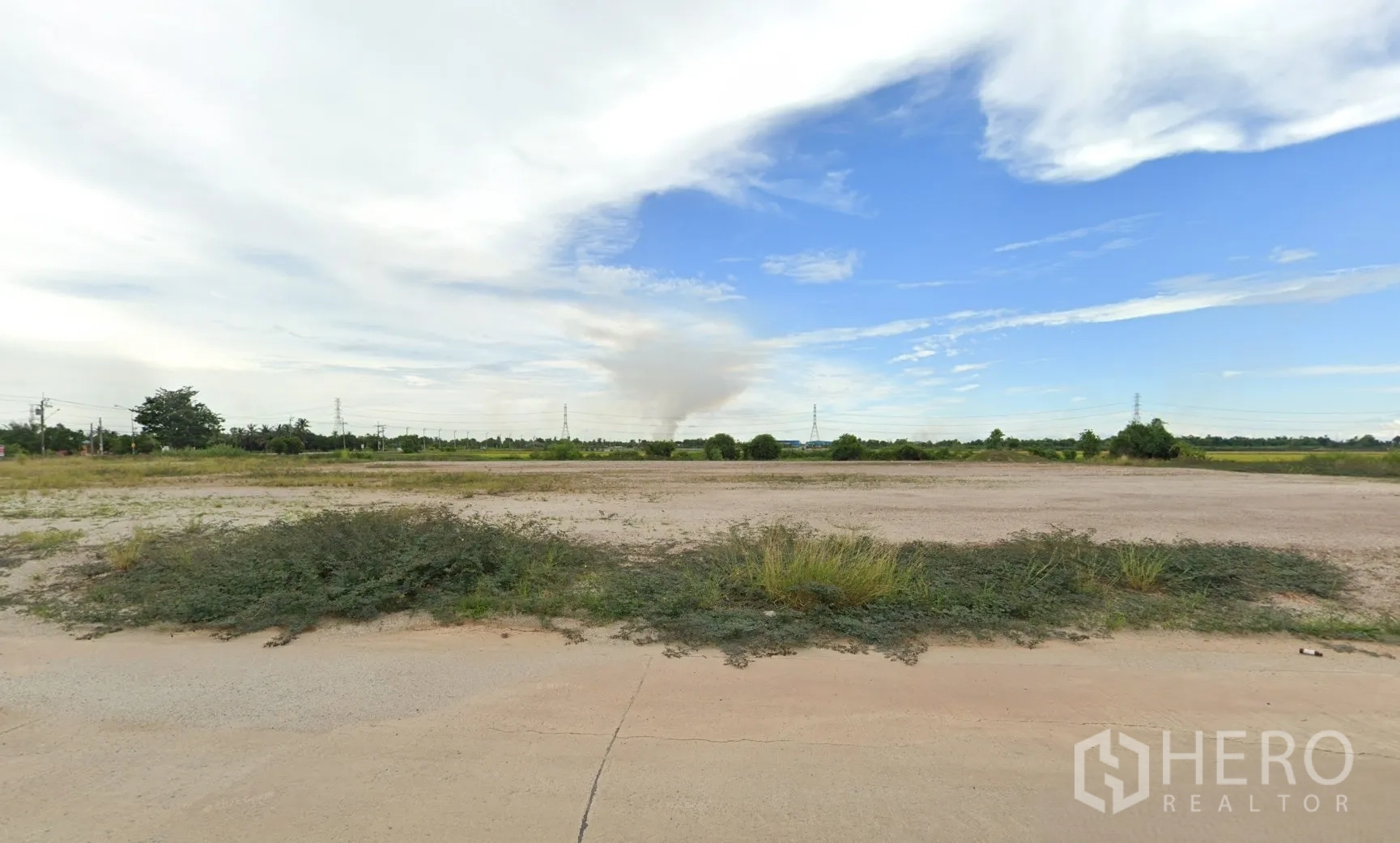 Land for sale in Sai Noi, Nonthaburi - Flat graded ground across a large site with shrubs and pylons in the distance.