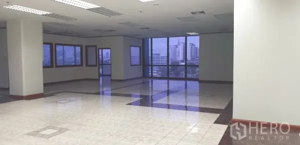 办公空间 出租在Din Daeng, Bangkok - 转角办公区，环绕玻璃与城市天际线视野，吊顶日光灯。