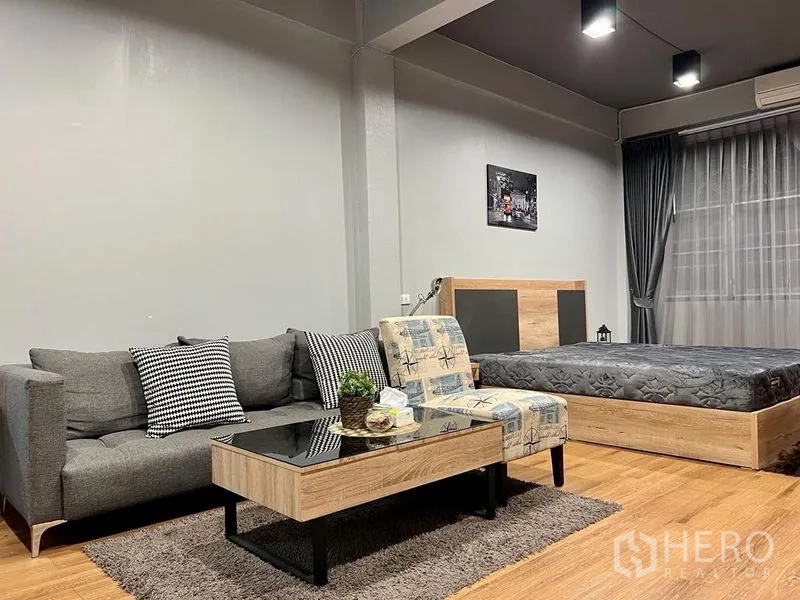 Shophouse for sale in Bang Kho Laem, Bangkok - Cozy seating corner beside a platform bed with coffee table and accent chair.