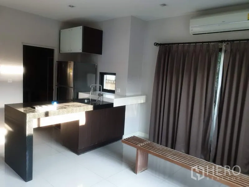 Detached House for sale in Bang Kapi, Bangkok - Kitchen zone with granite breakfast island, sink and access to a curtained sliding door.