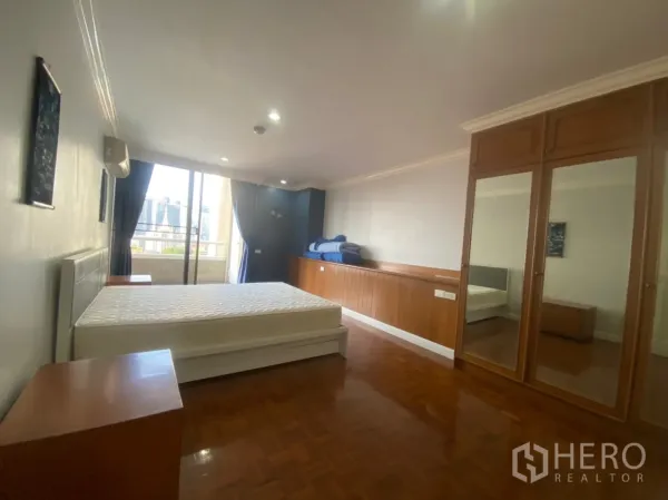 คอนโด ให้เช่าหรือขายในWatthana, Bangkok - ห้องนอนกว้าง มีตู้เสื้อผ้าบานกระจก เฟอร์ไม้ และทางออกสู่ระเบียงวิวเมือง