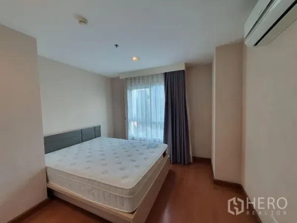 Condominium for rent in Huai Khwang, Bangkok - Bright master bedroom with queen bed, wood floors, AC and balcony door in Huai Khwang condo near MRT Phra Ram 9.