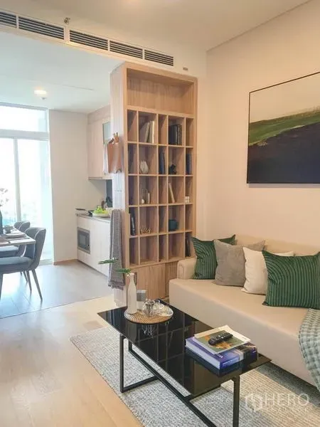 คอนโด ขายในKhlong Toei, Bangkok - ห้องนั่งเล่นสว่าง โซฟาสีเบจ โต๊ะกระจก และชั้นไม้กั้นพื้นที่ เชื่อมครัวและมุมทานอาหาร