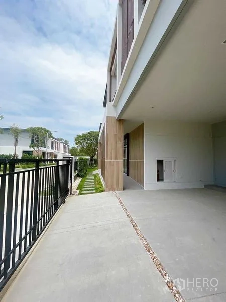 Detached House for sale in Don Mueang, Bangkok - Covered carport and side driveway with sliding gate next to a landscaped path.