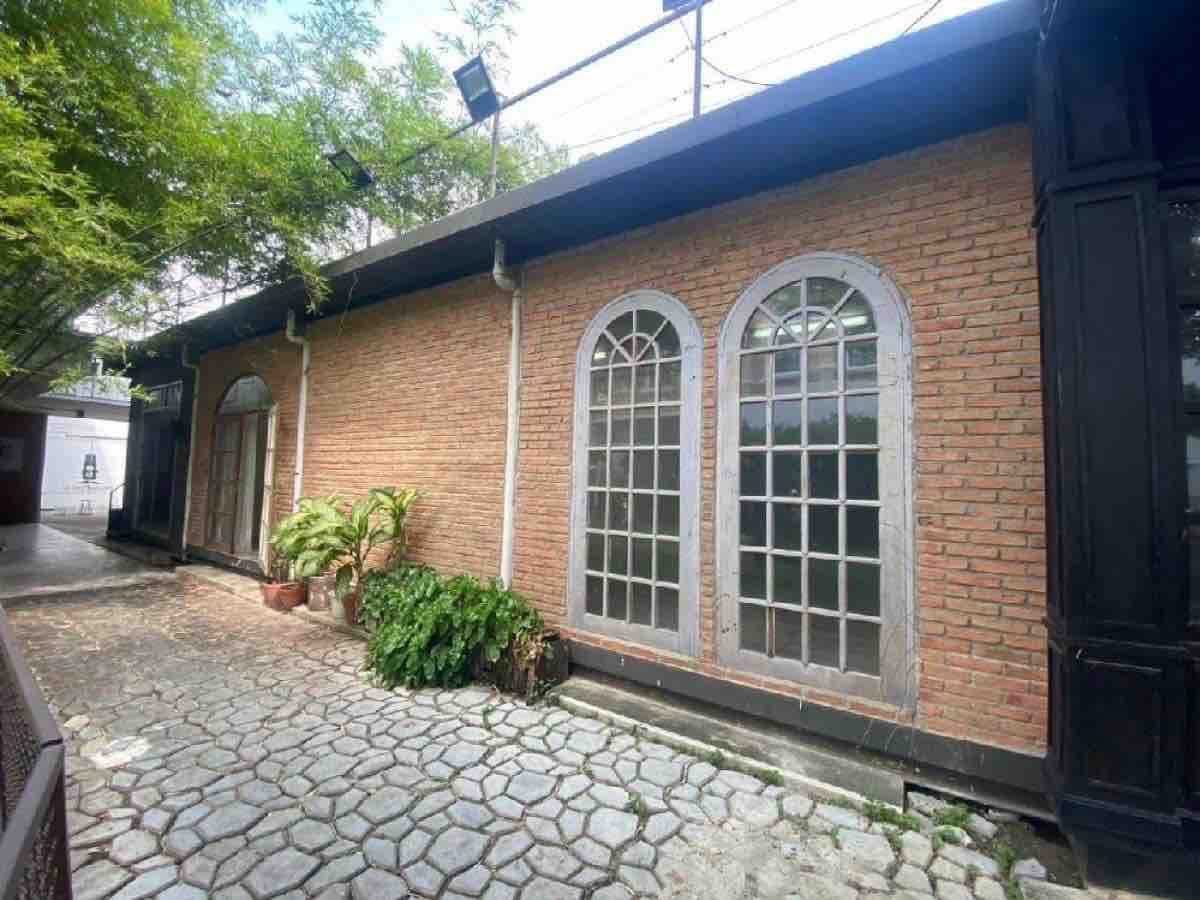 零售空间 出租在Watthana, Bangkok - 红砖外立面配拱形窗，旁有石板小径与盆栽。