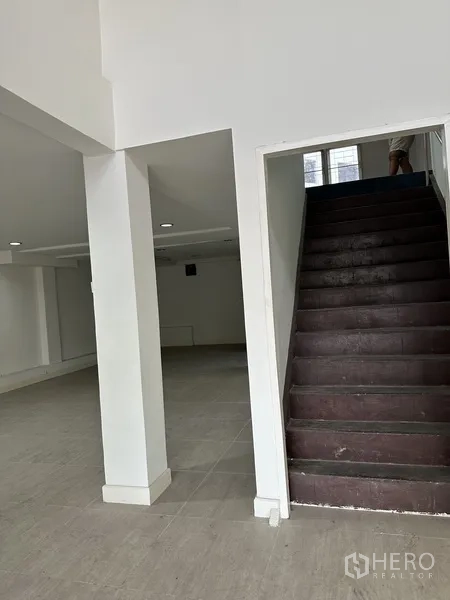 店屋 出租在Bang Na, Bangkok - 室内视角，坚固楼梯通往楼上，柱体支撑的开放空间。