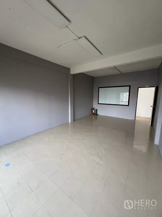 店屋 出租在Watthana, Bangkok - 空置多功能房，瓷砖地、灰墙与内窗。