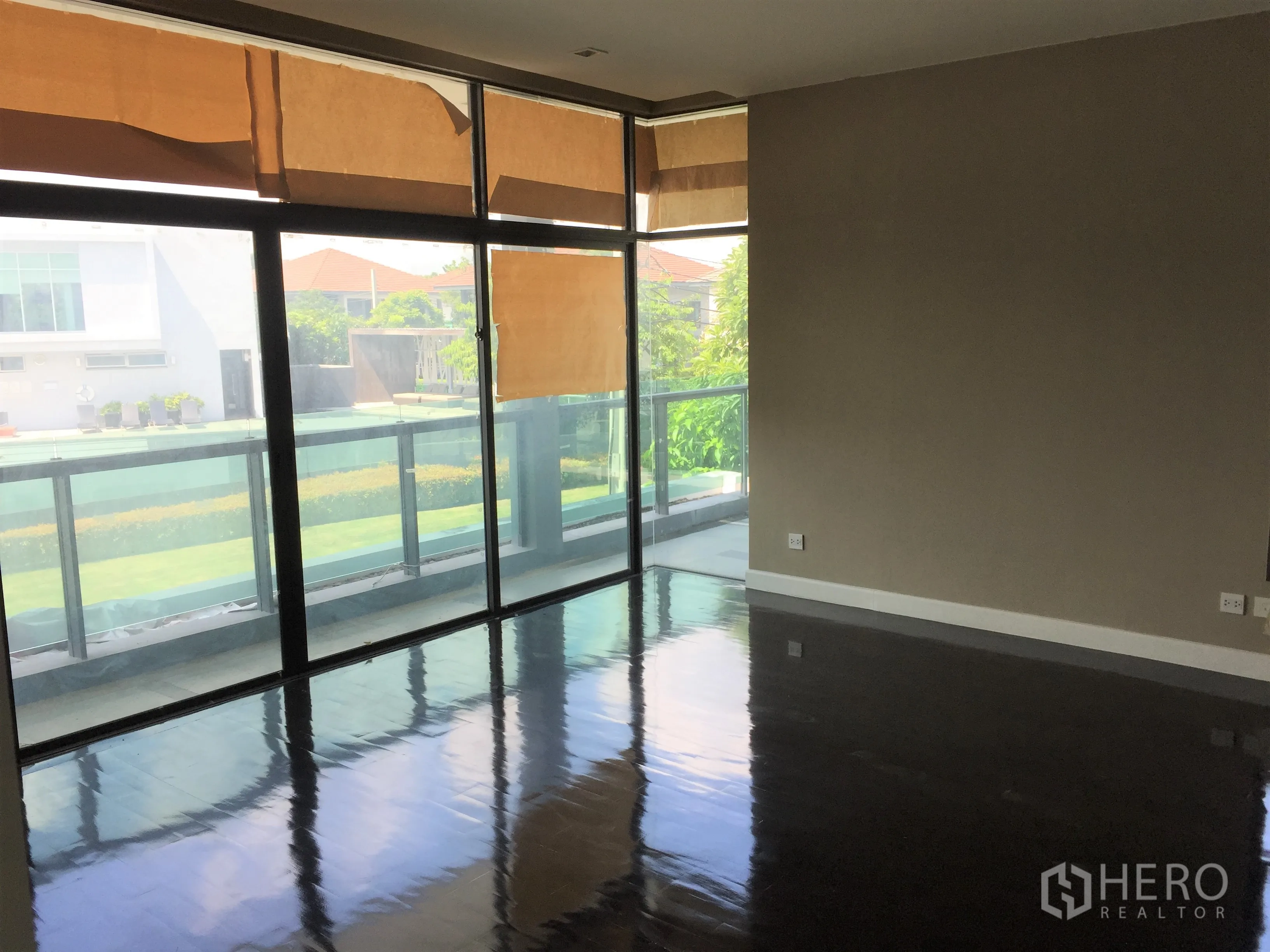 Detached House for rent or sale in Bang Kapi, Bangkok - Spacious upper bedroom with dark wood floors and a long glass-railed balcony.