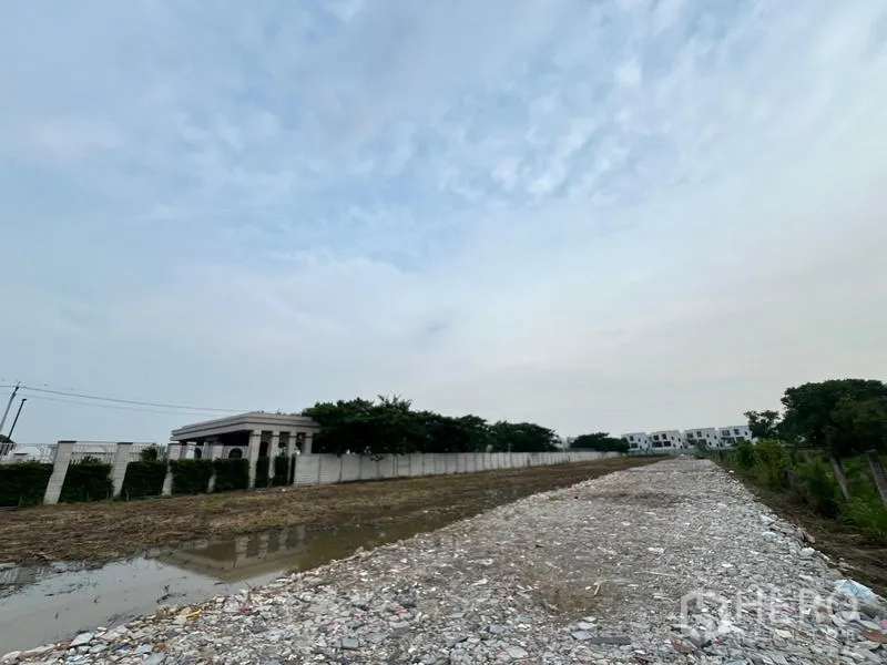 ที่ดิน ให้เช่าในLat Krabang, Bangkok - ทางลูกรังยกระดับผ่านกลางแปลง ข้างคูระบายน้ำและกำแพงรั้วสีขาว ในย่านเงียบสงบ