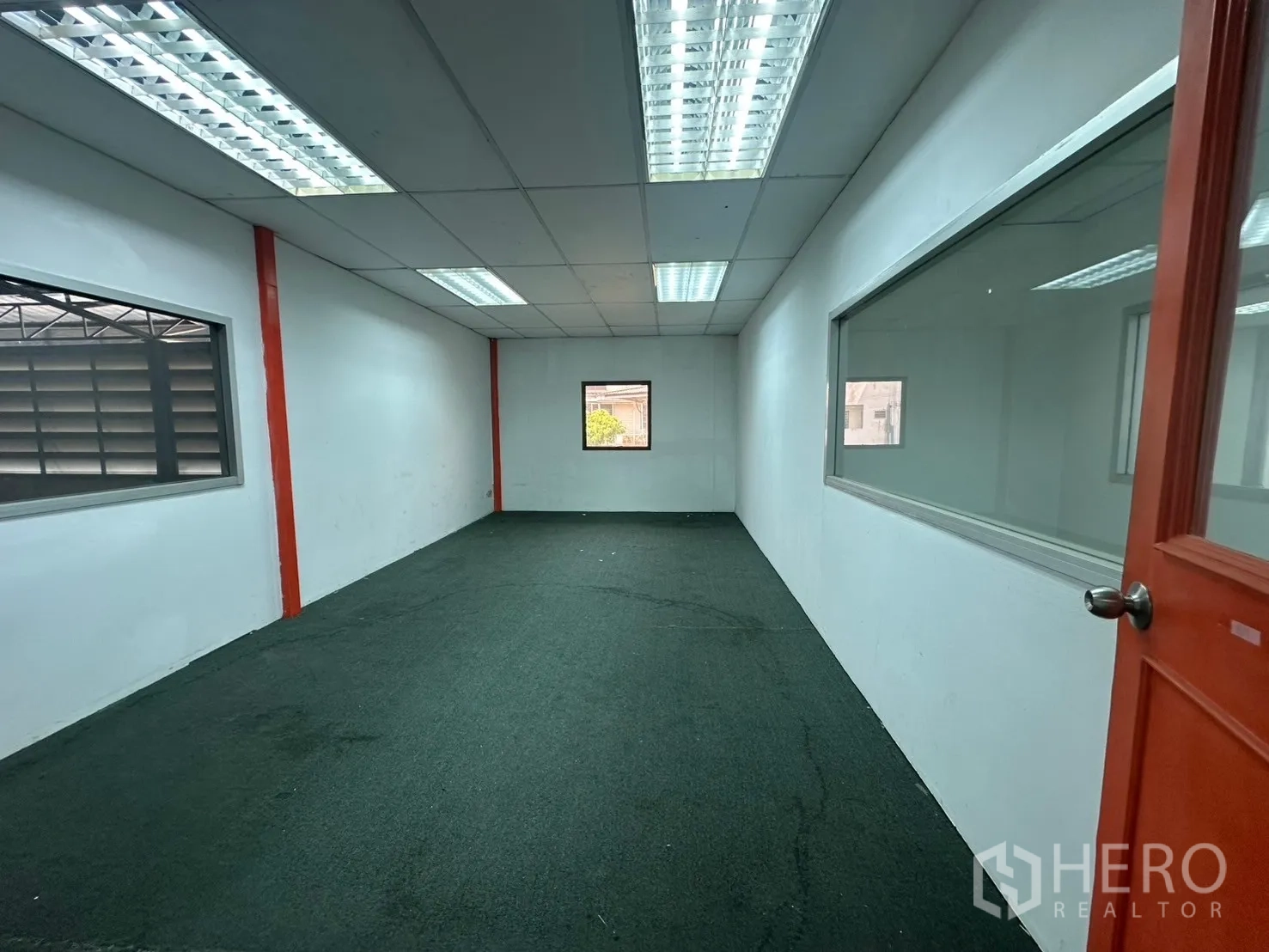 Warehouse for rent in Suan Luang, Bangkok - Long meeting room with carpet, fluorescent lighting and interior windows.