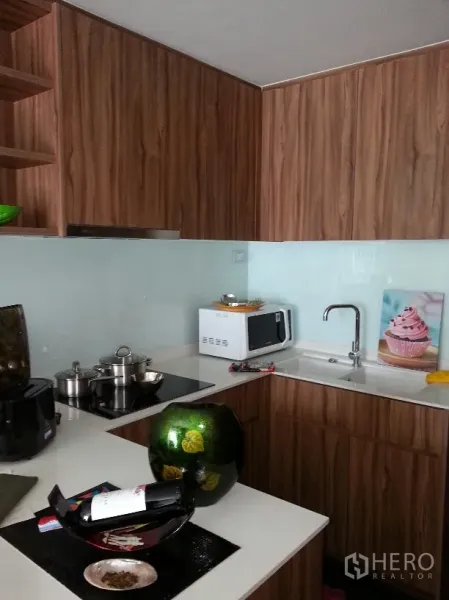 คอนโด ให้เช่าในWatthana, Bangkok - ครัวรูปตัวแอลสมัยใหม่ ตู้ลายไม้ เคาน์เตอร์สีขาว เตาไฟฟ้า ไมโครเวฟ และผนังกระจกกันเปื้อน
