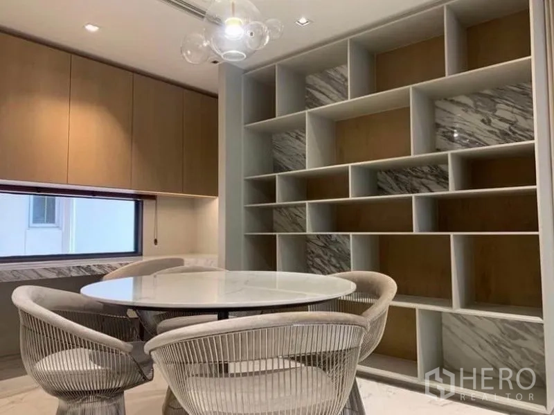 คอนโด ให้เช่าในWatthana, Bangkok - พื้นที่ทานข้าว โต๊ะกลม เก้าอี้ลายถัก และผนังชั้นวางบิวท์อินขนาดใหญ่