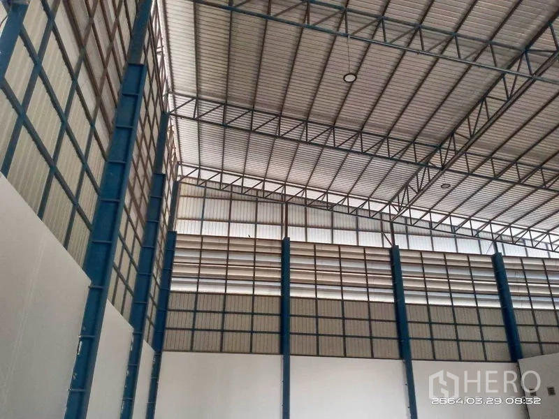 Warehouse for rent in Bang Bo, Samut Prakan - Tall interior wall with blue steel columns and daylight panels near the roofline.