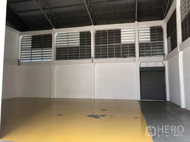 工厂 出租在Lam Luk Ka, Pathum Thani - 生产区设通风百叶与卷闸门，地面为黄色环氧地坪。