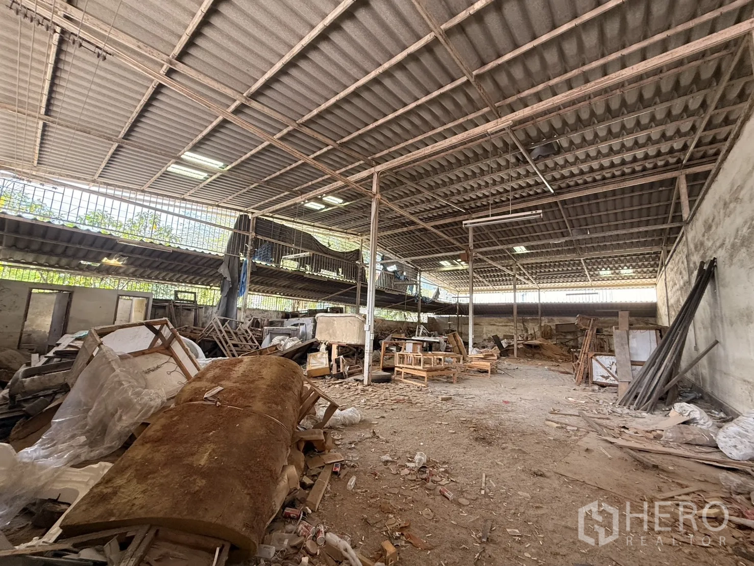 Warehouse for rent in Lam Luk Ka, Pathum Thani - Work area beneath ventilated eaves with timber and metal stock.