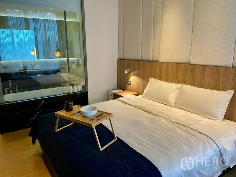 公寓 出租或出售在Bang Rak, Bangkok - 卧室配特大床与木质装饰，玻璃墙连通浴室