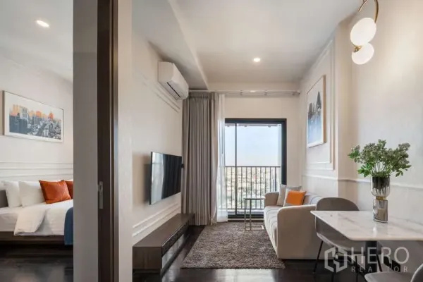 公寓 出租在Watthana, Bangkok - 明亮客厅，沙发、电视墙与阳台，并可见相连卧室