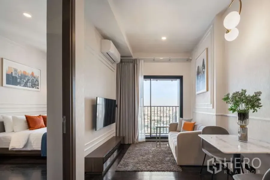 公寓 出租在Watthana, Bangkok - 明亮客厅，沙发、电视墙与阳台，并可见相连卧室