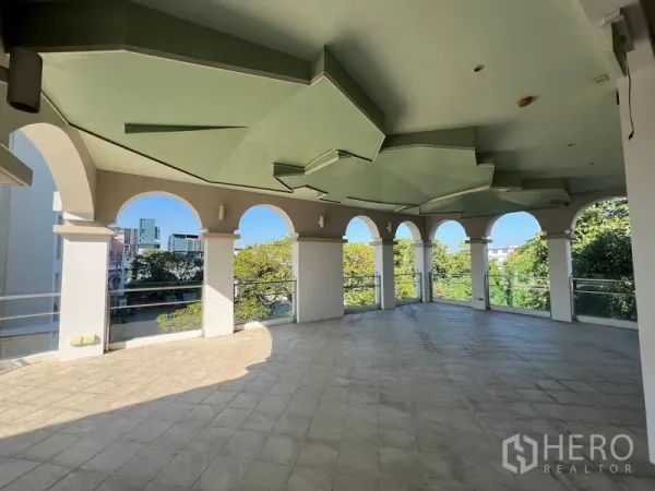 店屋 出租在Suan Luang, Bangkok - 宽敞的开放式阳台，拱门环绕，瓷砖地面俯瞰绿树。