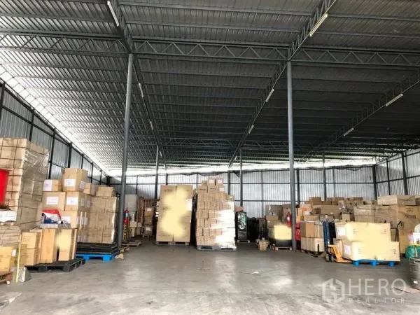 货栈 出租在Pak Kret, Nonthaburi - 仓库内部宽敞，钢柱结构与混凝土地面，堆放托盘纸箱。