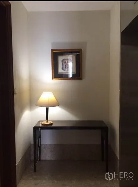 Condominium for rent in Watthana, Bangkok - Hallway nook with table lamp on a console and framed artwork above.
