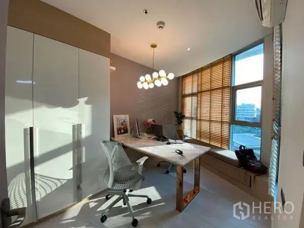公寓 出售在Huai Khwang, Bangkok - 明亮的家庭办公室，大书桌与现代吊灯，落地窗配木百叶，可见城市景观。