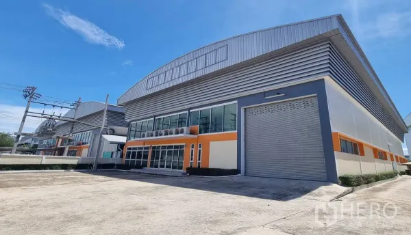 Factory for rent in Samut Prakan - Modern factory exterior with glass-front office and a large roller shutter in Phraeksa, Samut Prakan.