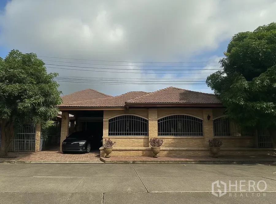 独立式住宅 出售在Pathum Thani - 单层独栋砖房，瓷瓦屋顶，带铁艺窗和前车道车棚。