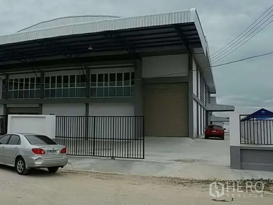 货栈 出租在Bang Bo, Samut Prakan - 工业仓库立面，黑色安全大门与停车空间。
