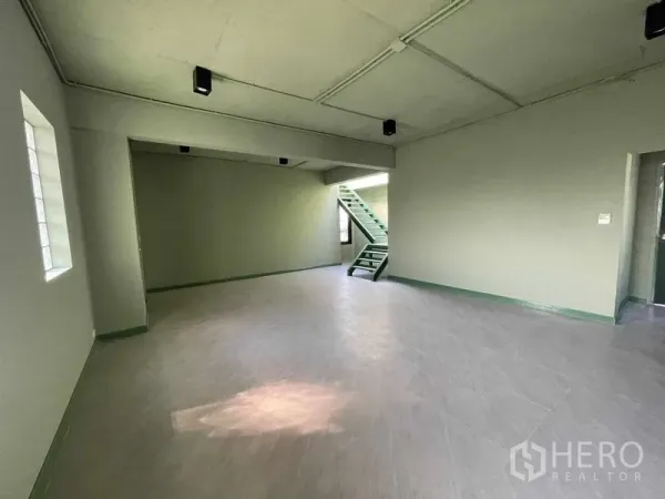Home Office for rent in Phaya Thai, Bangkok - Open workspace with a green metal staircase and multiple windows ready for fit-out.