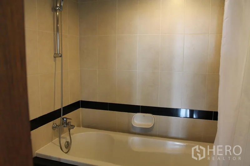 房间 出租在Bang Rak, Bangkok - 铺砖浴室，带浴缸和手持花洒。