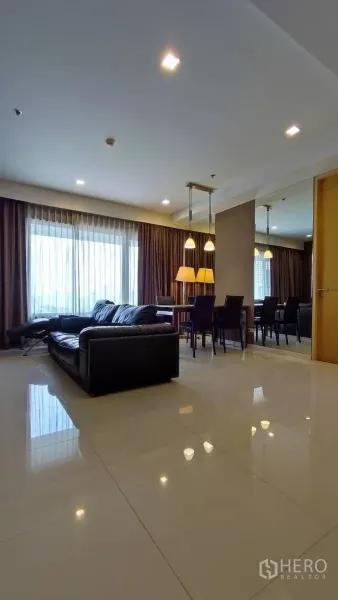Condominium for rent in Sathon, Bangkok - Bright open-plan living and dining area with leather sofa, dining set, pendant lights, large curtained windows and glossy tile floor.