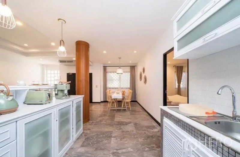 Detached House for rent in Ratchathewi, Bangkok - Open-plan kitchen flowing to dining area with stone-look floors.