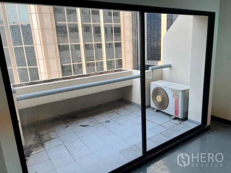 办公空间 出租在Pathum Wan, Bangkok - 小阳台设室外空调机组，透过落地玻璃可见城市建筑景观。