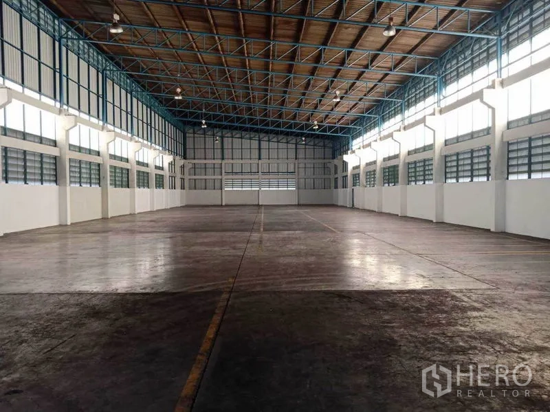 工厂 出租在Samut Prakan - 对称式仓储风格内部，高棚灯与耐用混凝土地坪。