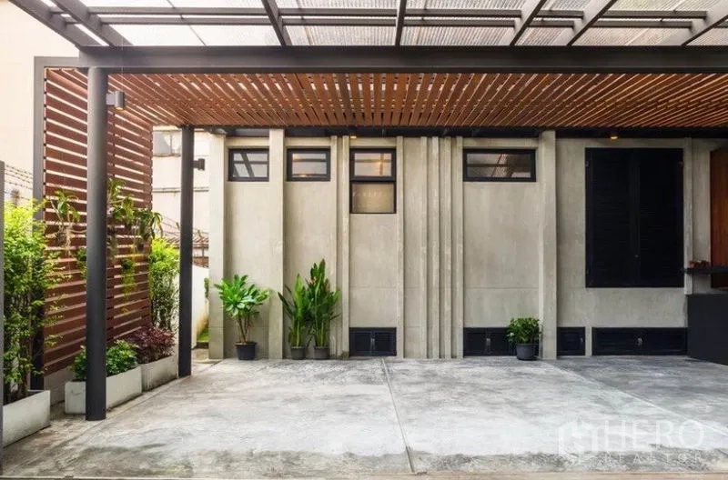ทาวน์เฮาส์ ให้เช่าในKhlong Toei, Bangkok - ที่จอดรถมีหลังคาระแนงไม้ ผนังคอนกรีต และต้นไม้กระถาง