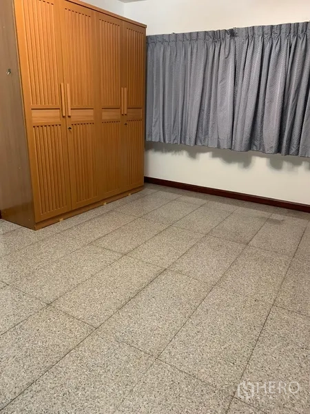 Condominium for rent in Sathon, Bangkok - Spare bedroom with large wooden wardrobe and curtained window on stone-tile flooring.