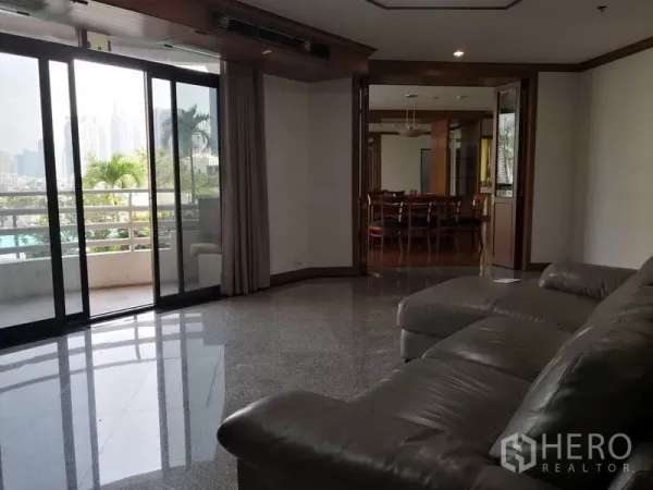 公寓 出租在Khlong Toei, Bangkok - 客厅连接宽阳台，可望城市天际与棕榈树，玻璃门后为餐厅